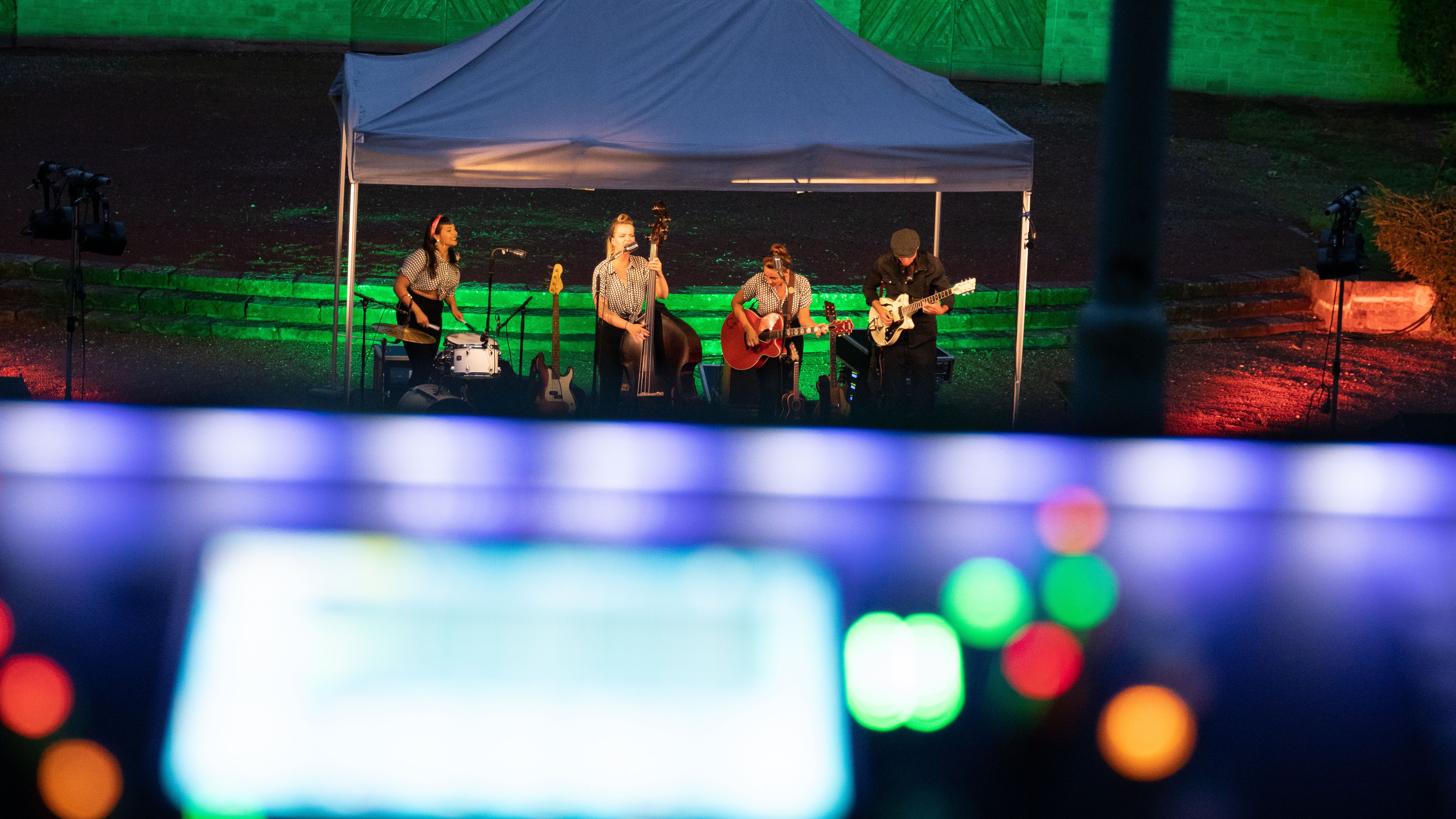 Im Vordergrund bunte Lichter, im Hintergrund spielt eine Band unter einem Pavillon auf der Freilichtbühne Wattenscheid.