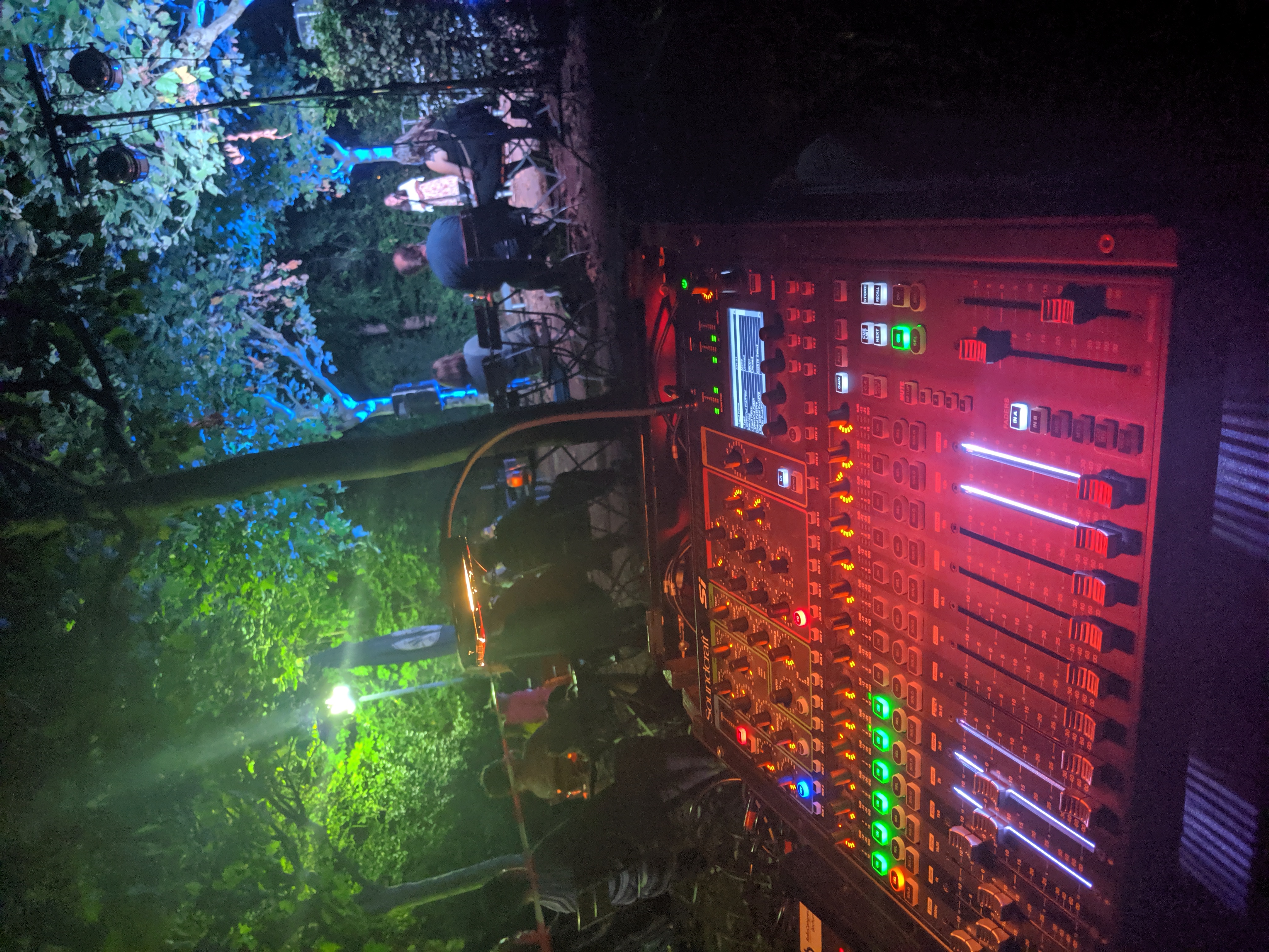 Colourfully lit mixing desk at the Freilichtbühne Wattenscheid. Trees can be seen in the background.